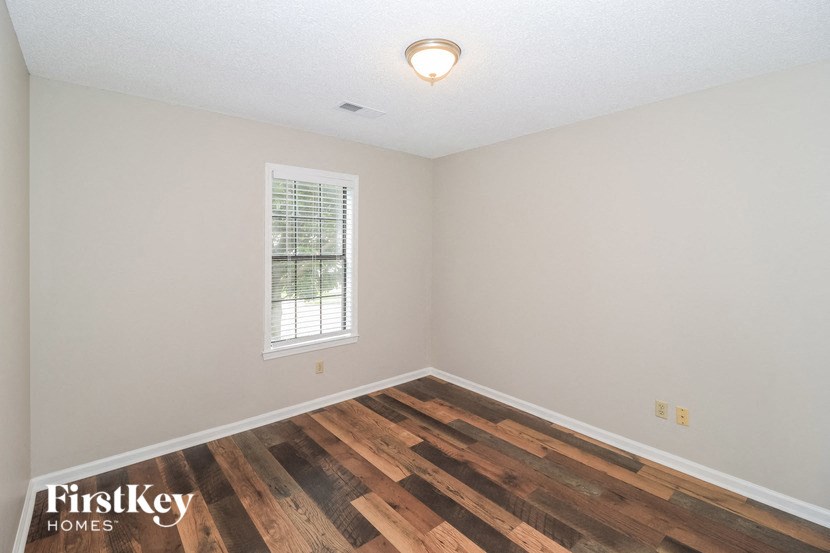 the living room of a home with wood flooring and a window