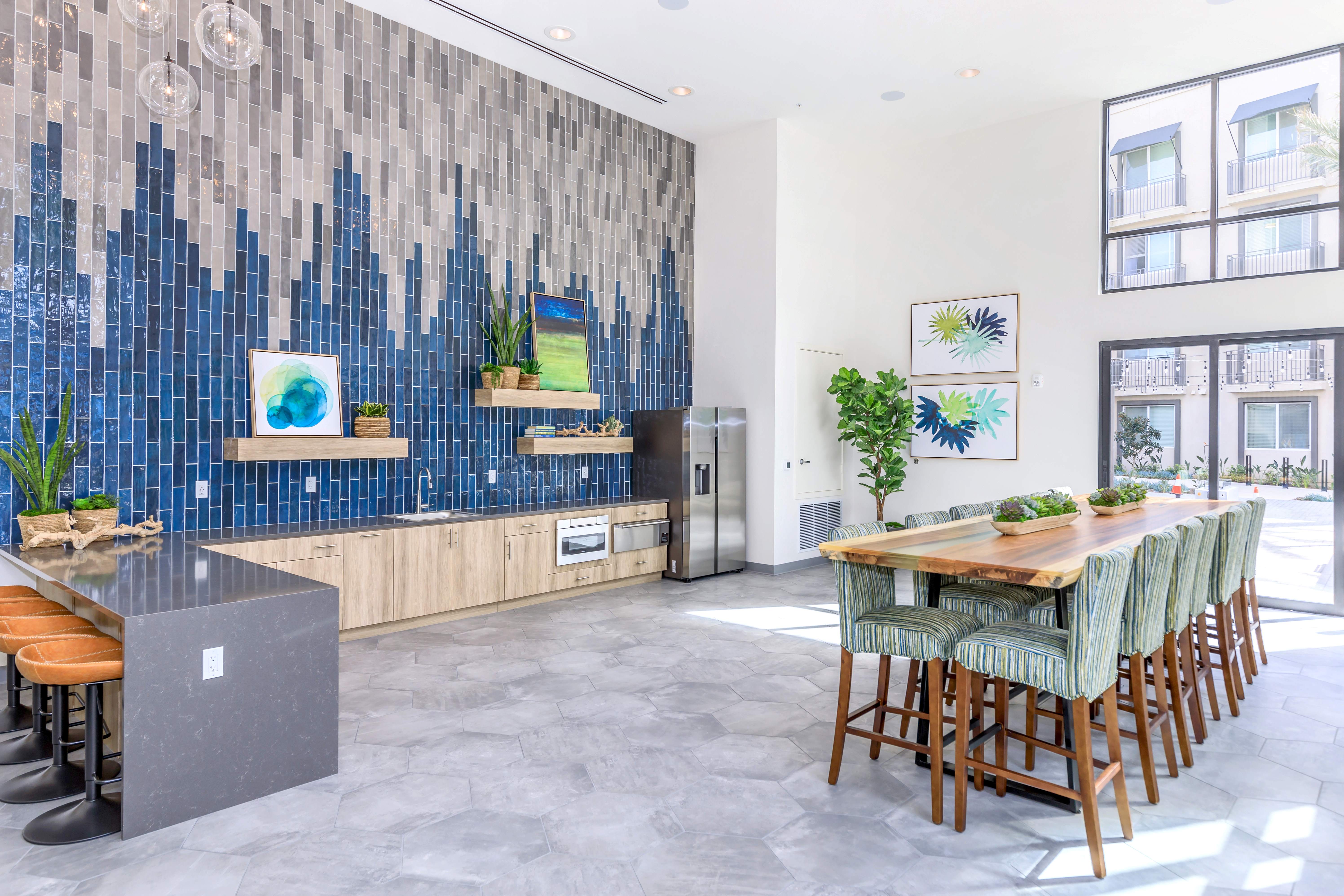 A modern kitchen with a blue tiled backsplash and wooden furniture.