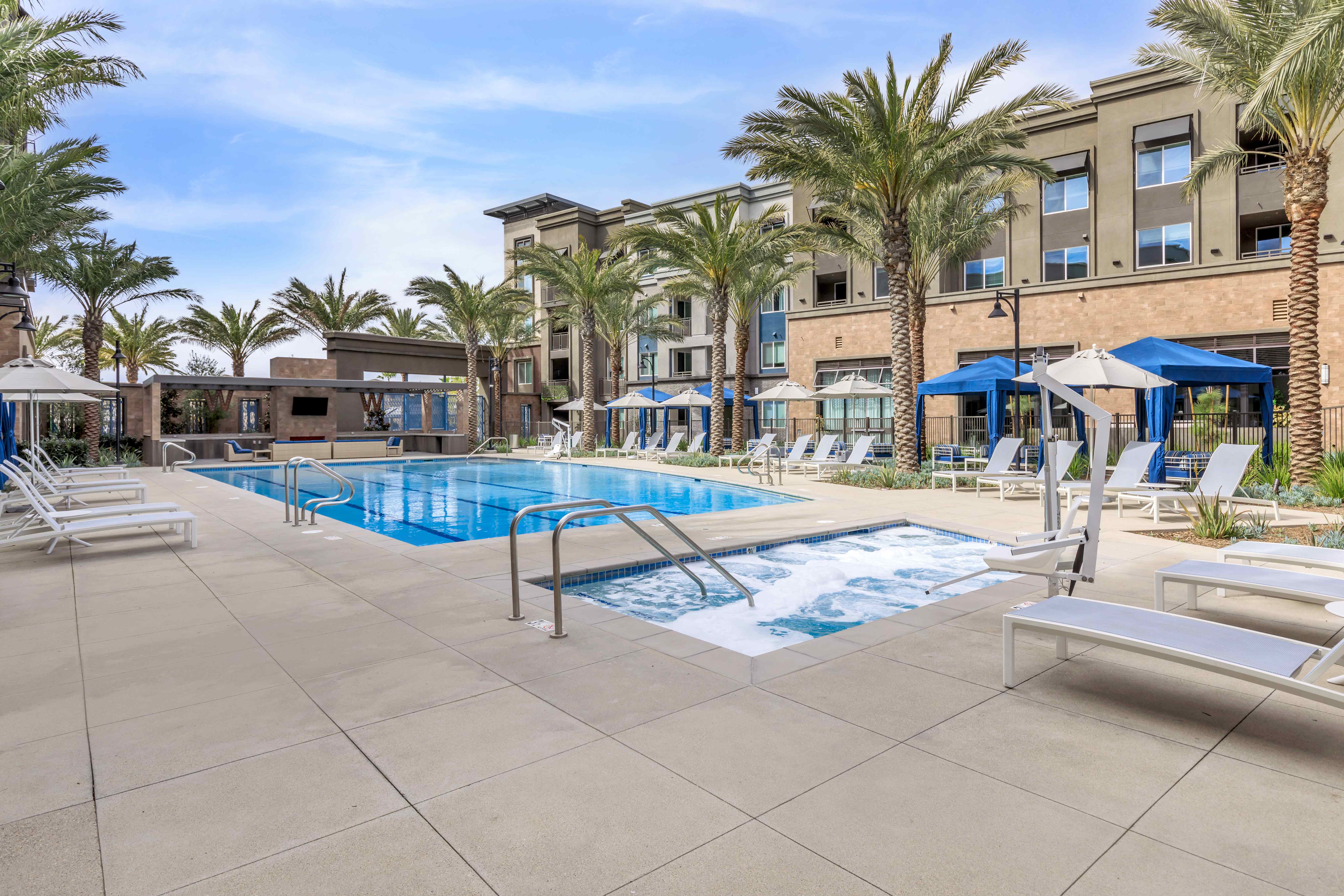 A pool surrounded by palm trees and lounge chairs.