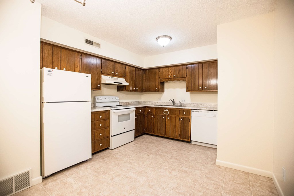 A kitchen with white appliances and wooden cabinets.