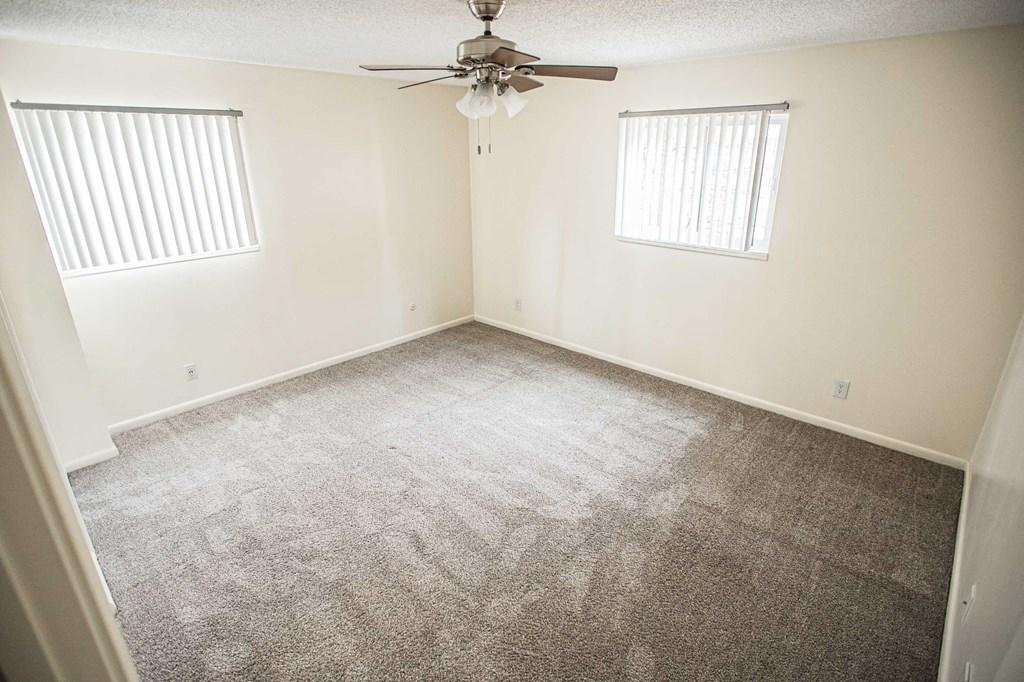 A room with a ceiling fan and carpeted floor.