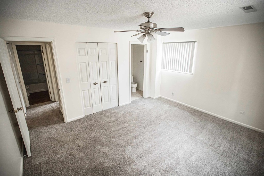 A room with a ceiling fan and carpeted floor.