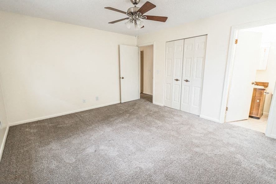A room with a ceiling fan and carpeted floor.