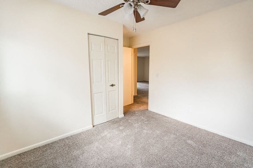 A room with a ceiling fan and a door.