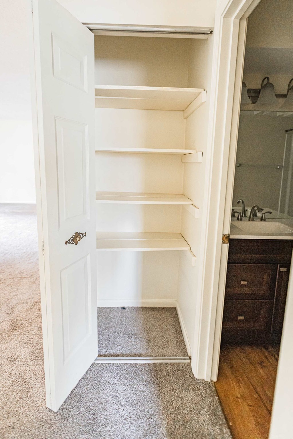 A white door with a handle is open to a room with a carpeted floor.
