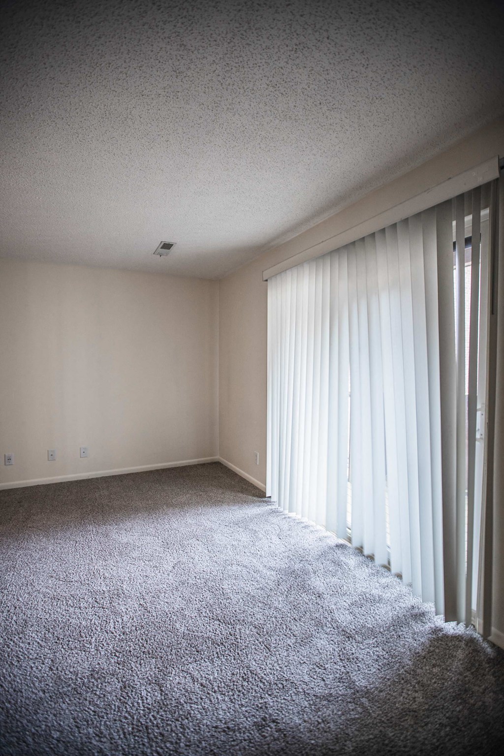 A room with a carpeted floor and a window with curtains.