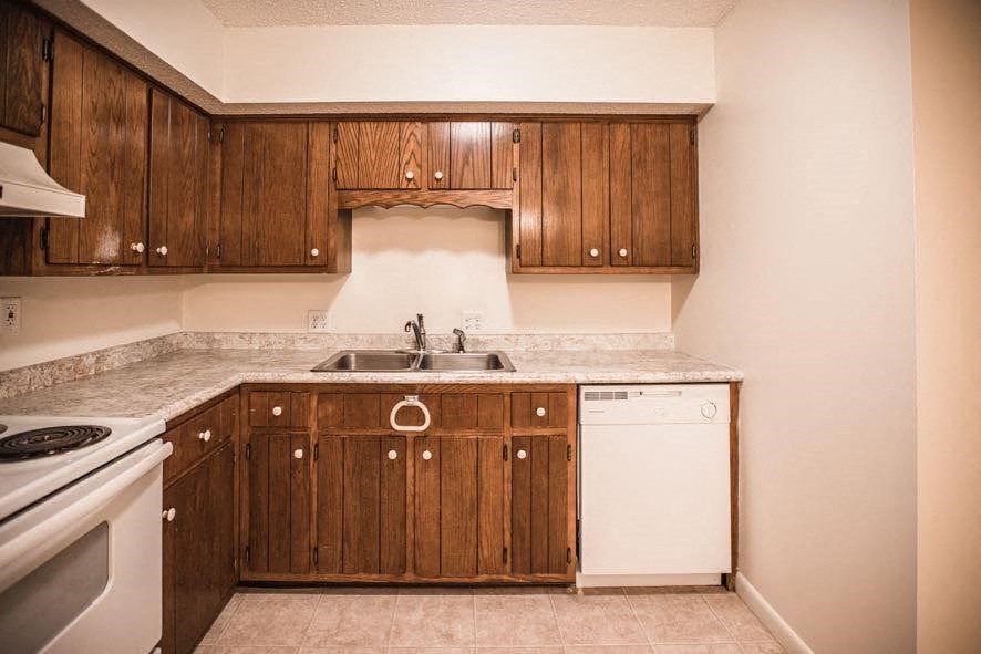 A kitchen with wooden cabinets and a white dishwasher.