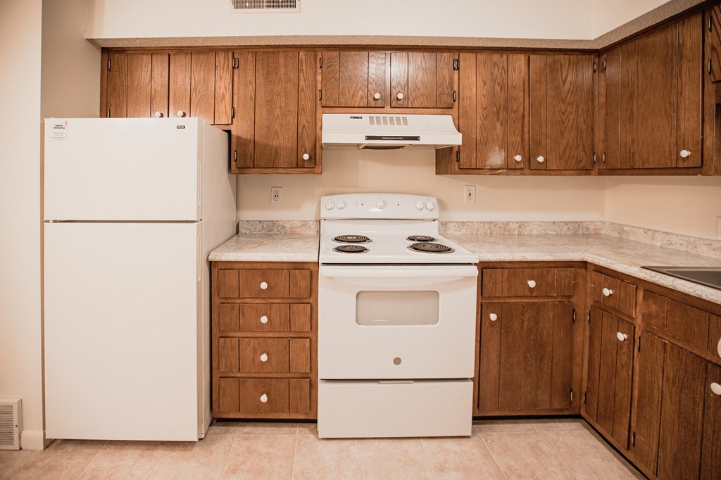 A white refrigerator is in a kitchen with wooden cabinets.