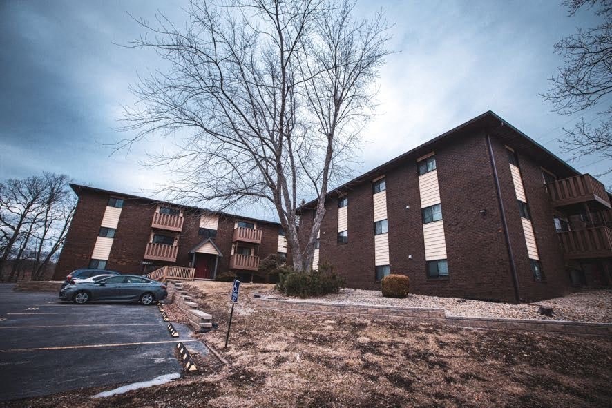 A car is parked in front of a brick apartment building.