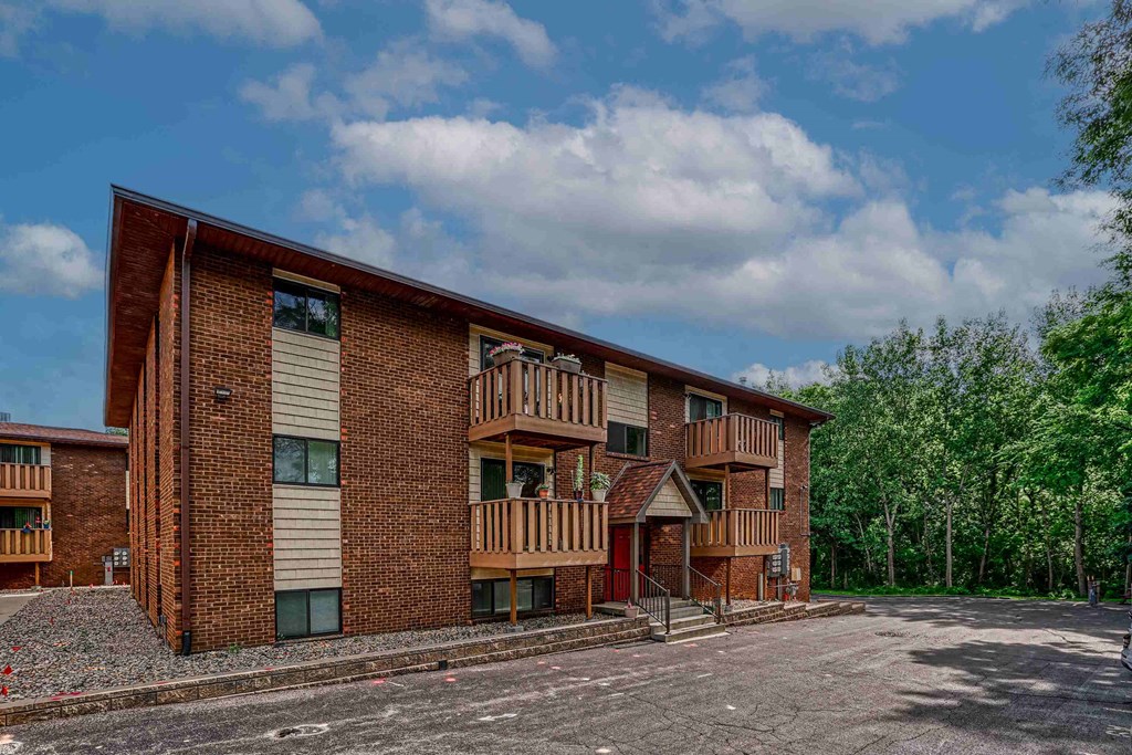 A large brick building with a balcony and a red door.