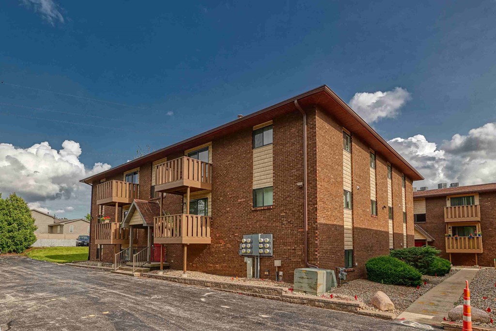 A large brick apartment building with a parking lot in front.
