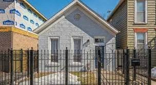 A small house with a black fence in front.