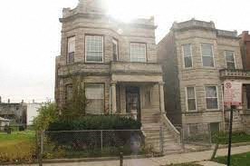 A large, old, two-story house with a fence in front.