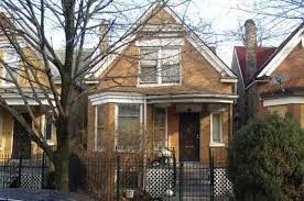 A brick house with a black iron fence in front.