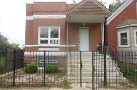 A red brick house with a white door and a black fence.