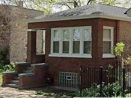 A small red brick house with a black fence in front.