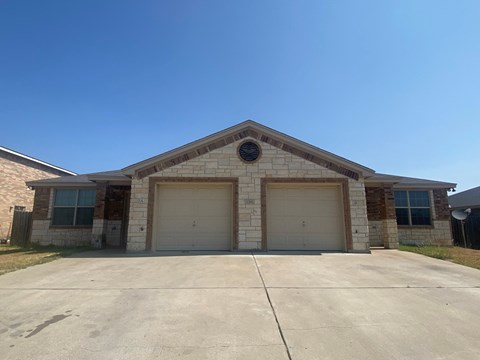 a brick house with two garage doors and a clear blue sky