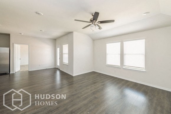 an empty living room with wood floors and a ceiling fan