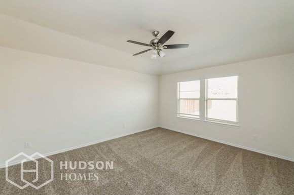 an empty living room with a ceiling fan and a window