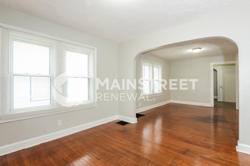 a living room with a hardwood floor and a large window