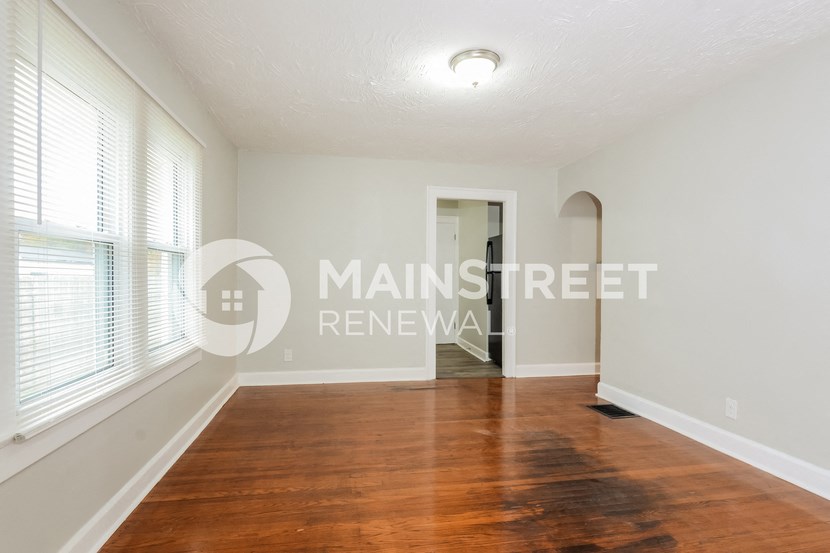 a bedroom with a hard wood floor and large windows