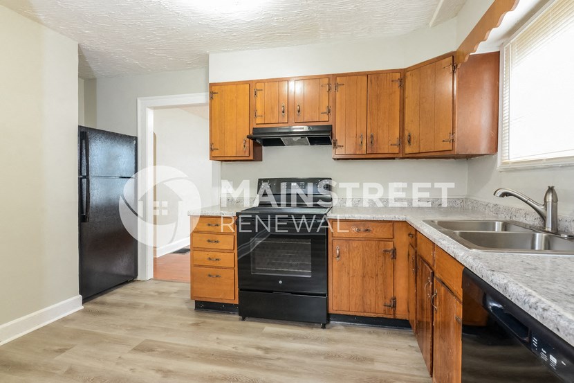 a kitchen with wooden cabinets and a sink and black appliances