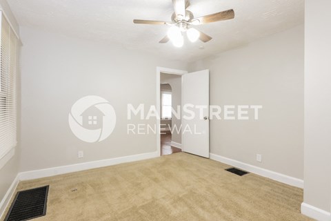 a living room with carpet and a ceiling fan