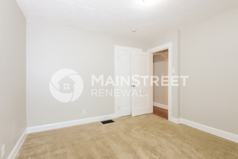a bedroom with a door to a closet and a carpeted floor