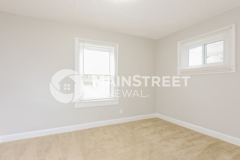 two windows in a room with beige carpet