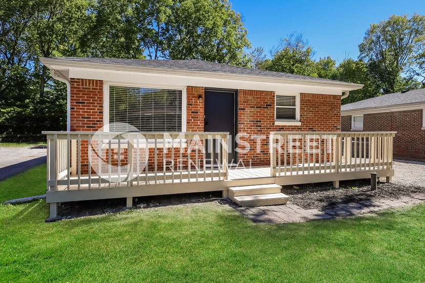 a porch with a white railing in front of a brick house