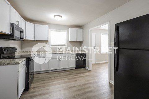 a renovated kitchen with white cabinets and a black refrigerator
