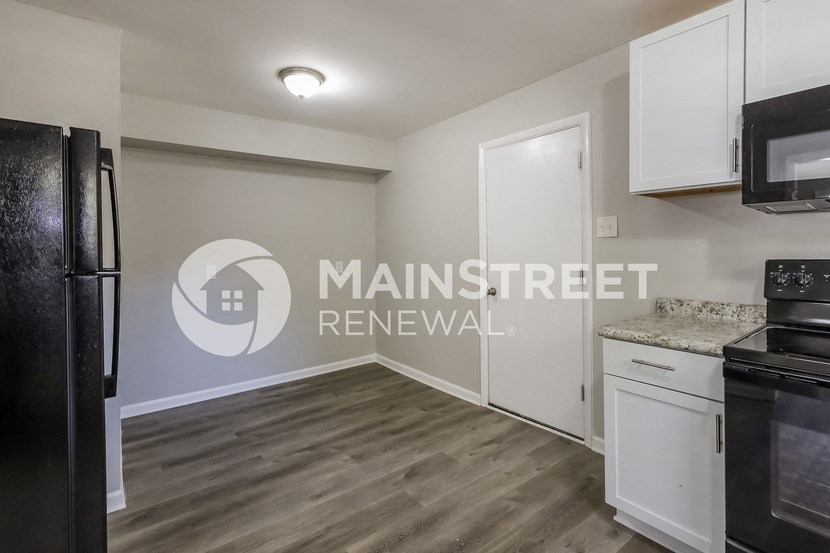 a renovated kitchen with white cabinets and a black refrigerator