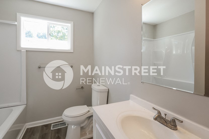 a bathroom with a sink and a toilet and a window