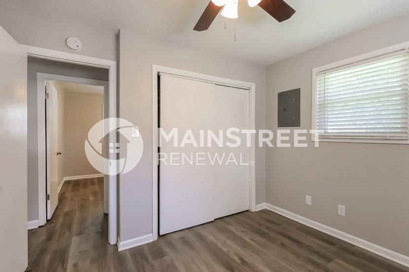 a living room with a door to a hallway and a window
