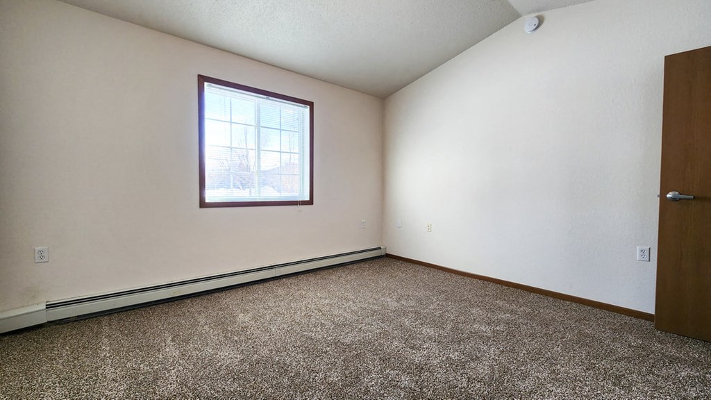 an empty room with a window and carpet