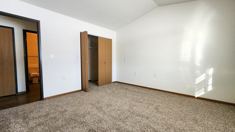 a bedroom with white walls and wood flooring and a closet
