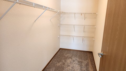 a walk in closet with empty shelves and a door