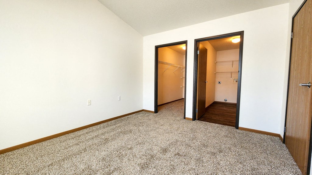 a bedroom with a door to a closet and a carpeted floor