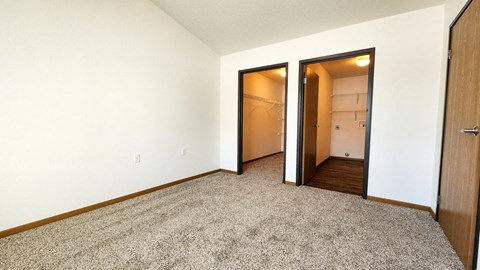 a bedroom with a door to a closet and a carpeted floor