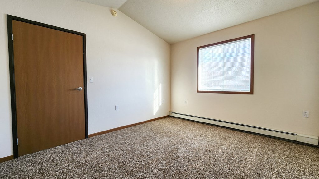 a bedroom with a door and a window and a carpeted floor