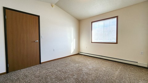 a bedroom with a door and a window and a carpeted floor