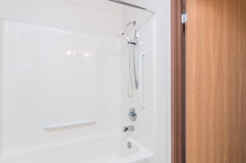 a white shower in a bathroom with a wooden door