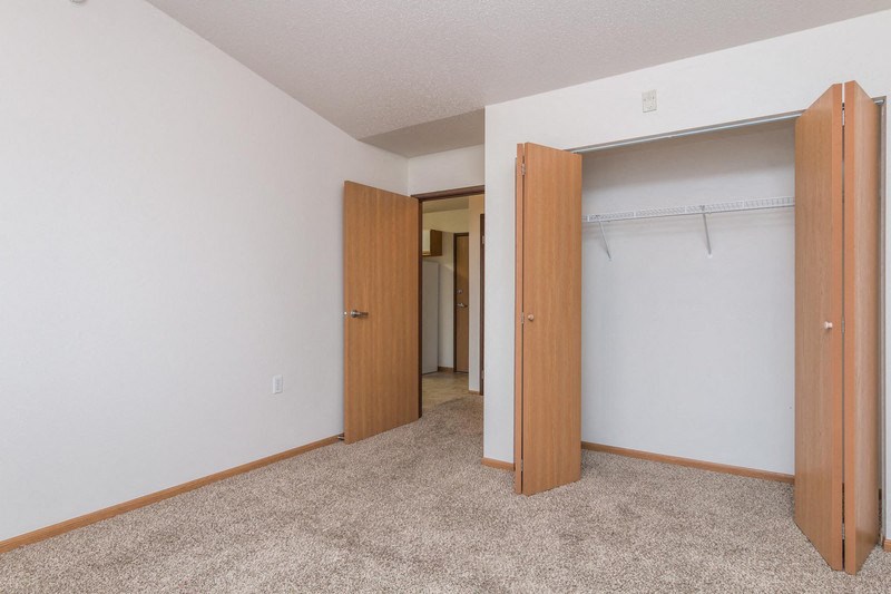 an empty bedroom with two doors and a closet