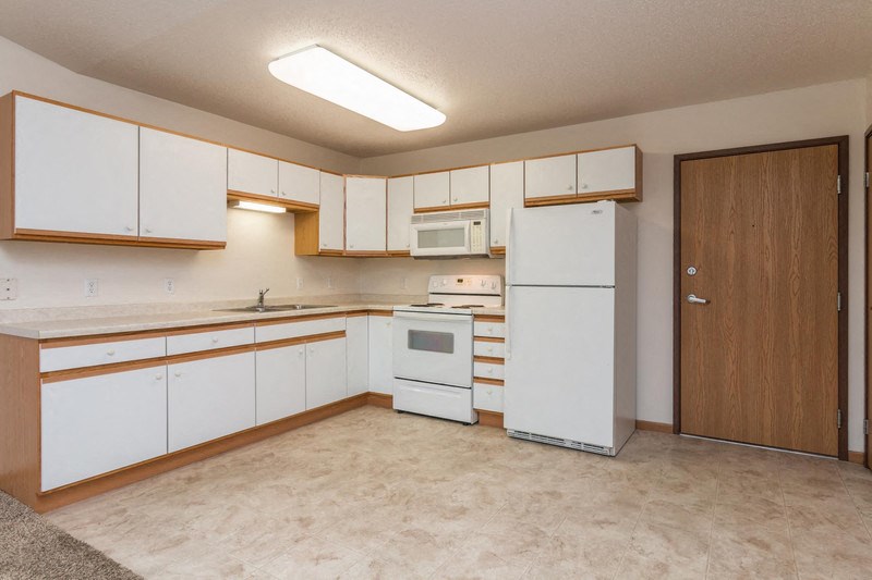 an empty kitchen with white appliances and white cabinets
