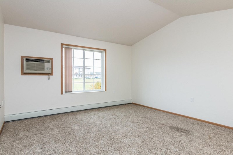 an empty room with a window and carpet