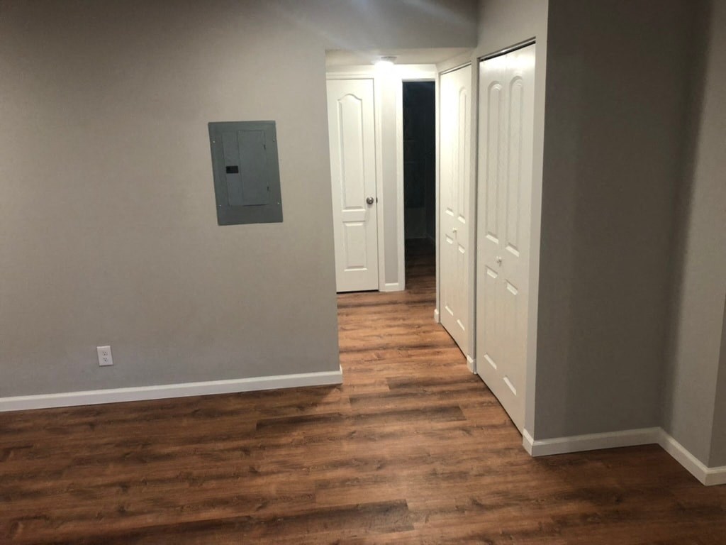 a living room with a hard wood floor and a door to a hallway