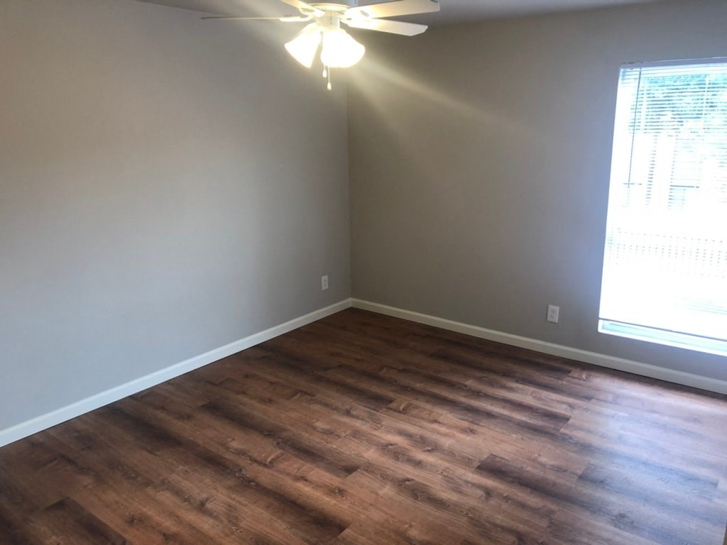 a living room with wood floors and a ceiling fan