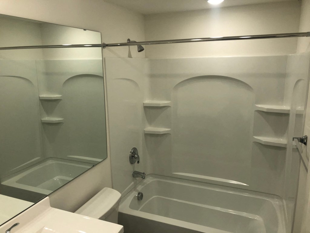 a white bathroom with a shower and a sink