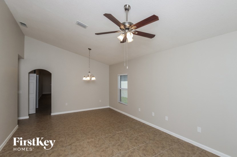 A spacious room with a ceiling fan and two chandeliers.