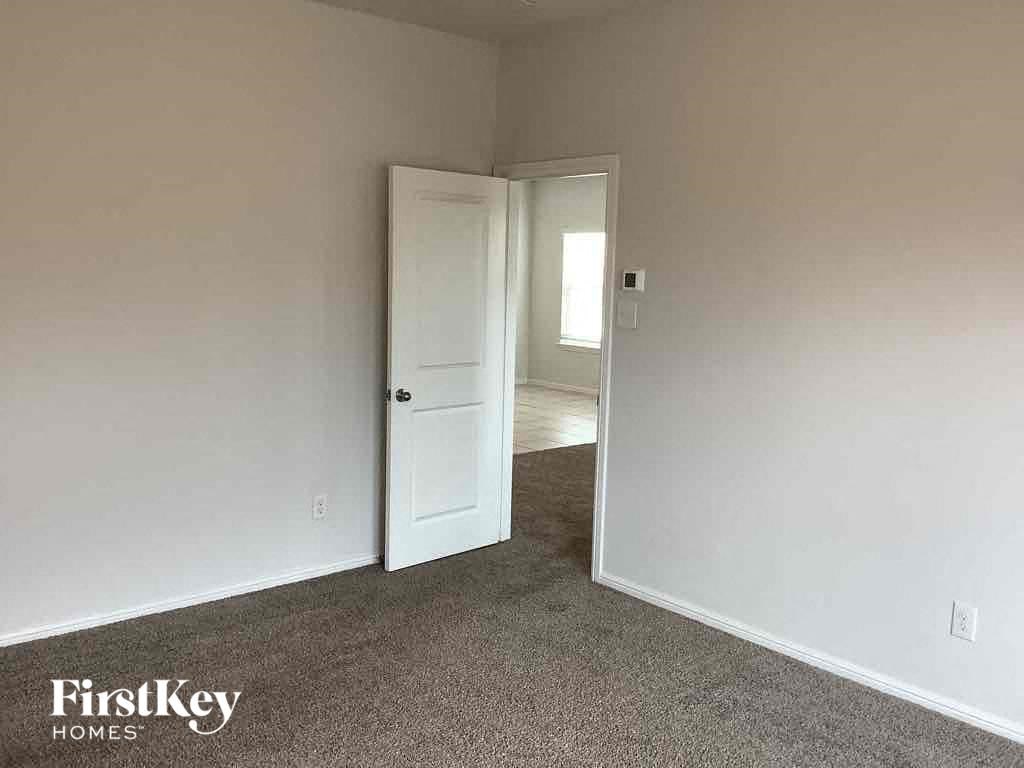 an empty bedroom with a white door and carpeted floor